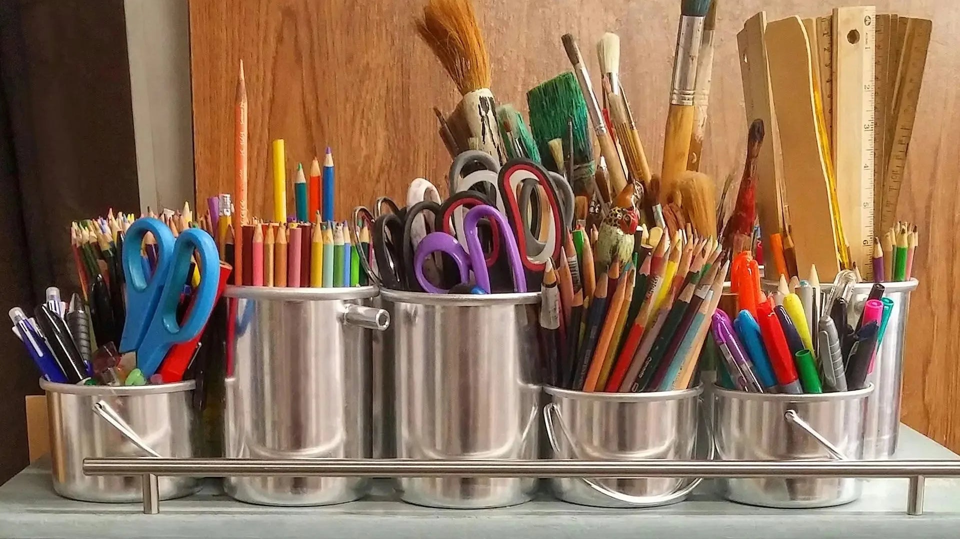 A collection of pencils, pens, scissors, rules and brushes in metal containers