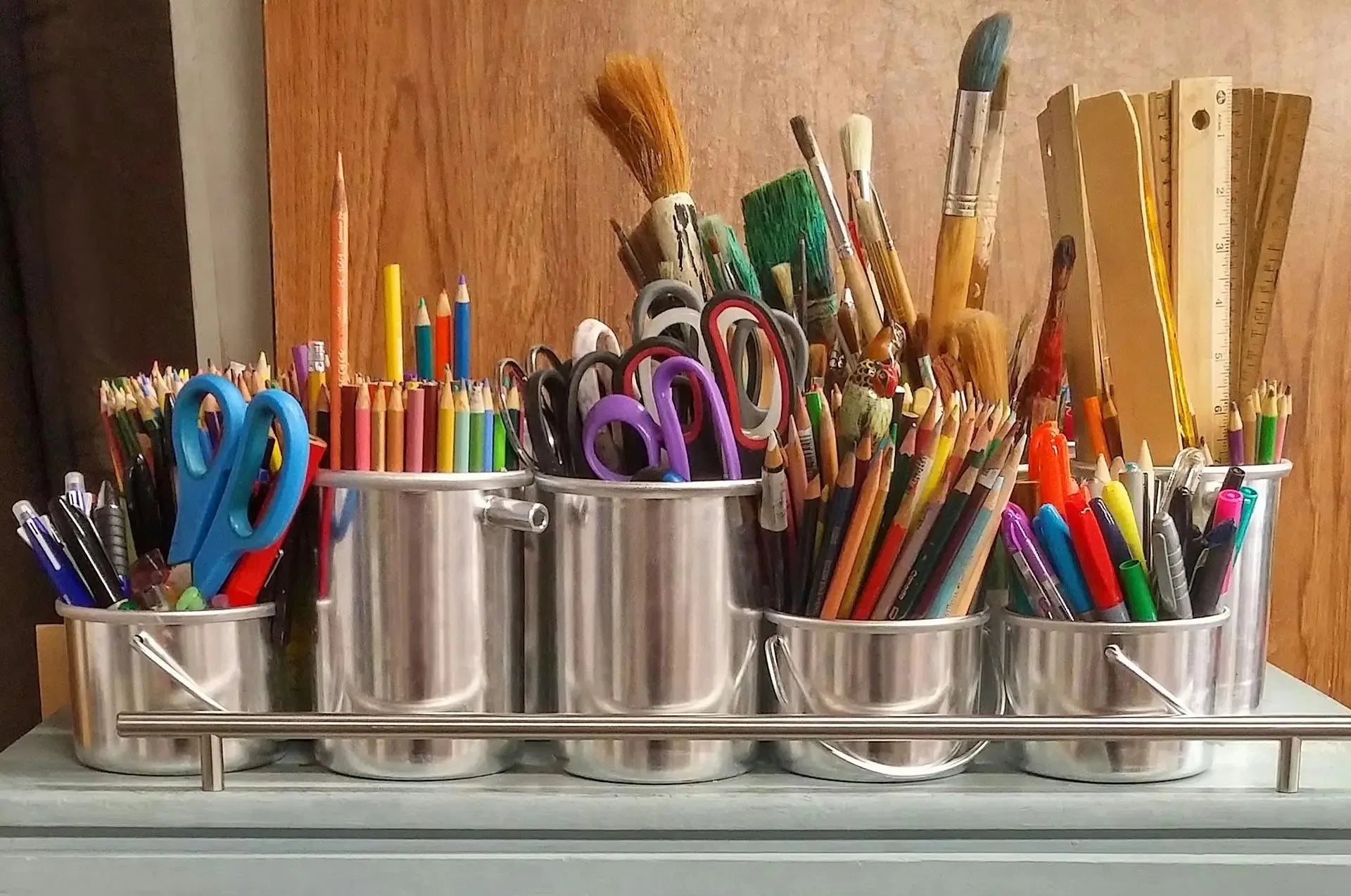 A collection of pencils, pens, scissors, rules and brushes in metal containers