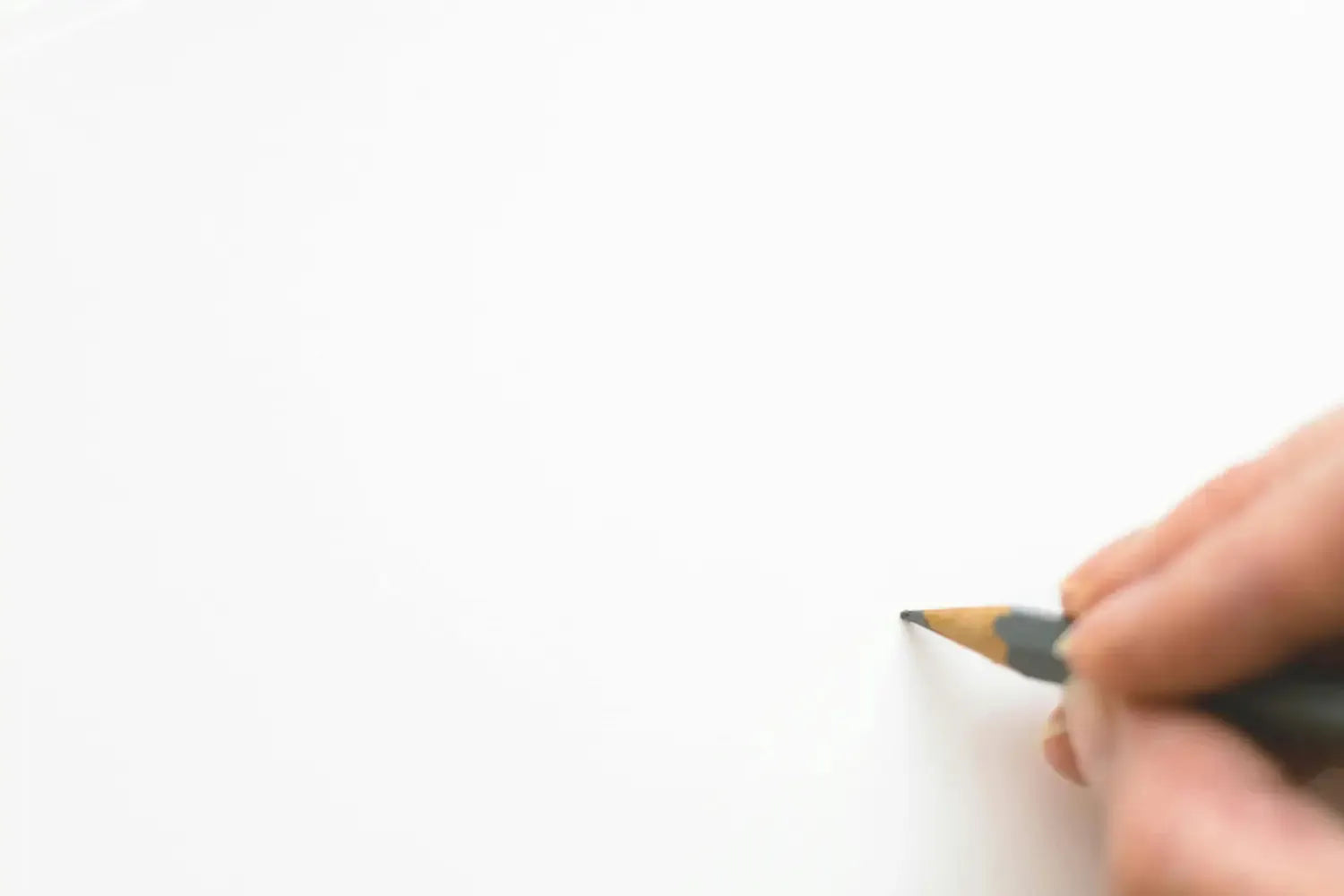 A person holding a pencil against a blank page