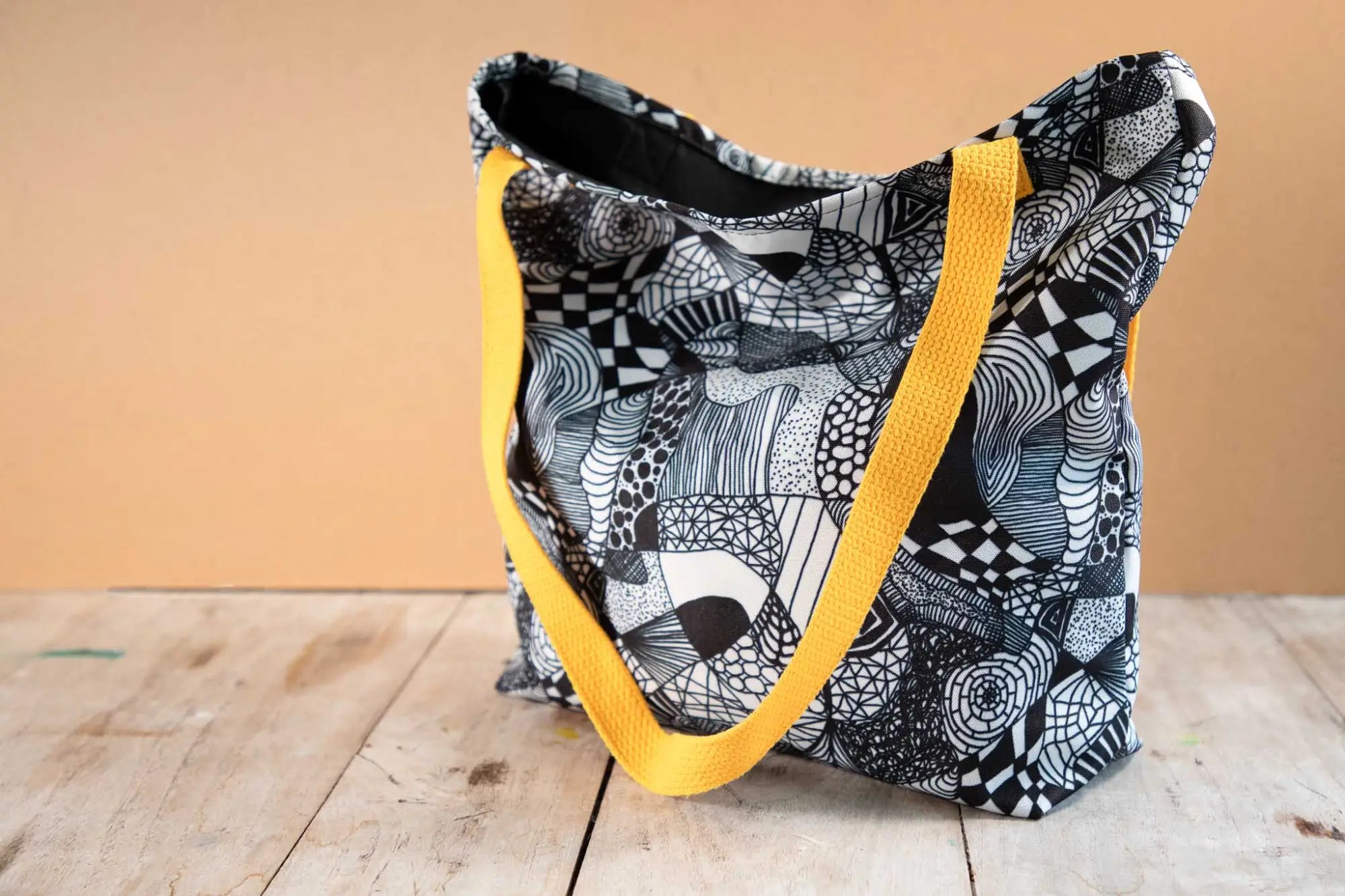 Tote bag with black and white patterned fabric and a yellow strap.