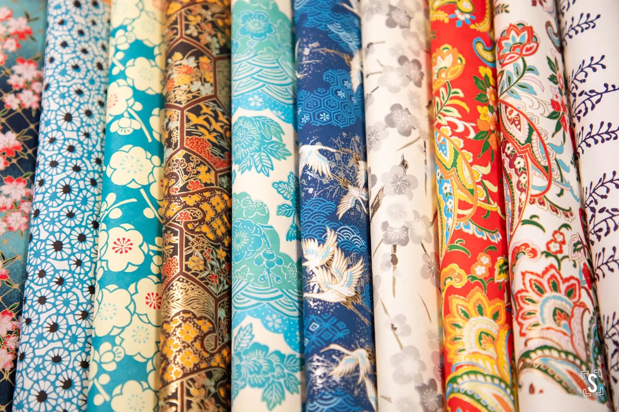 Colorful patterned fabric rolls displayed side by side.