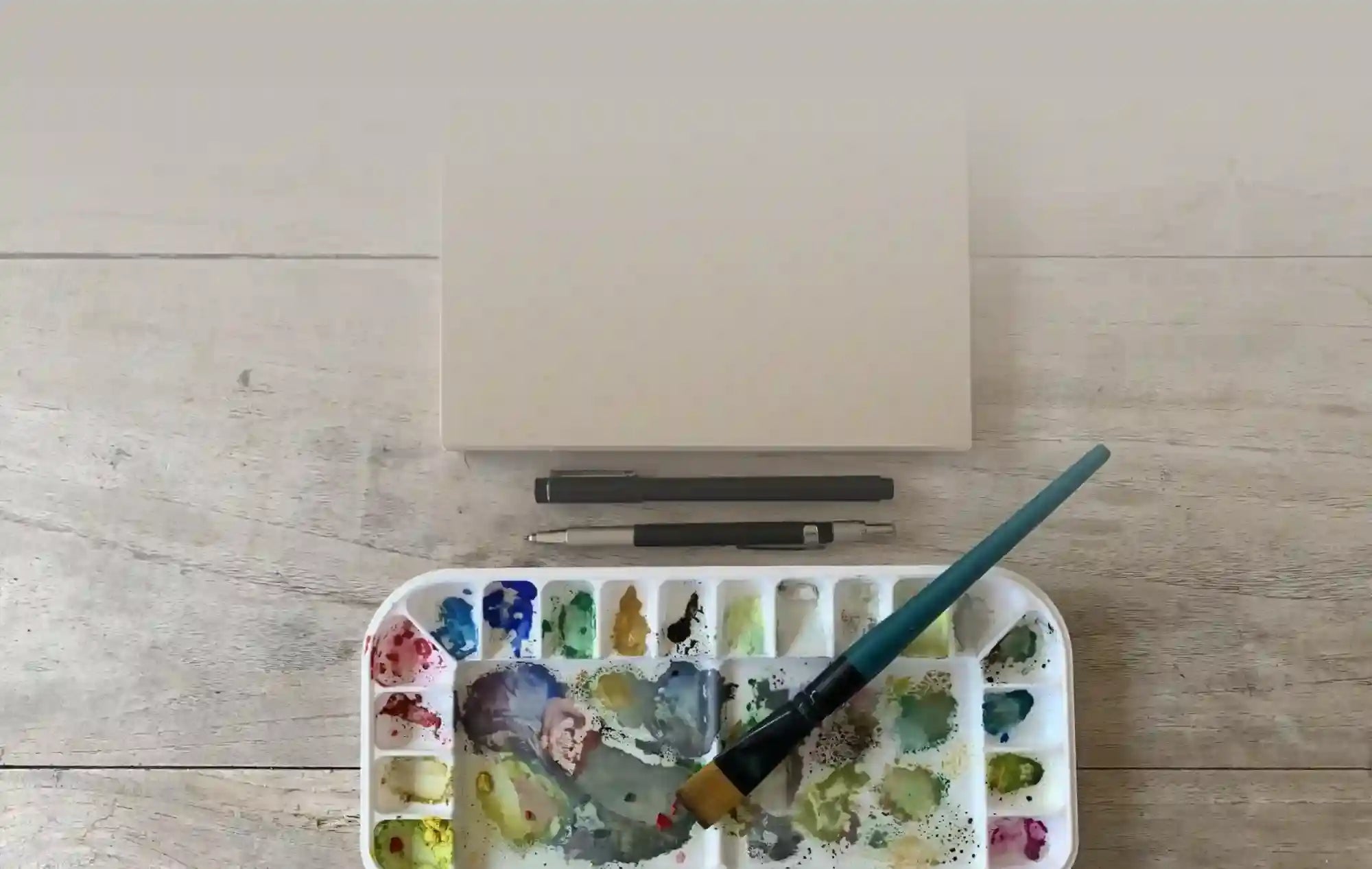 Artist’s palette filled with colorful watercolor paints and a brush.