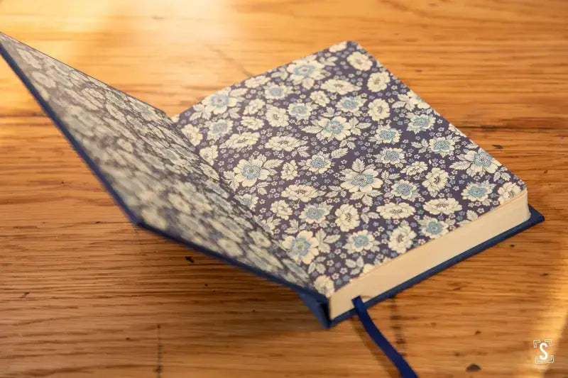 Book with blue and white floral cover and ribbon bookmark for the Bookbinding Workshop