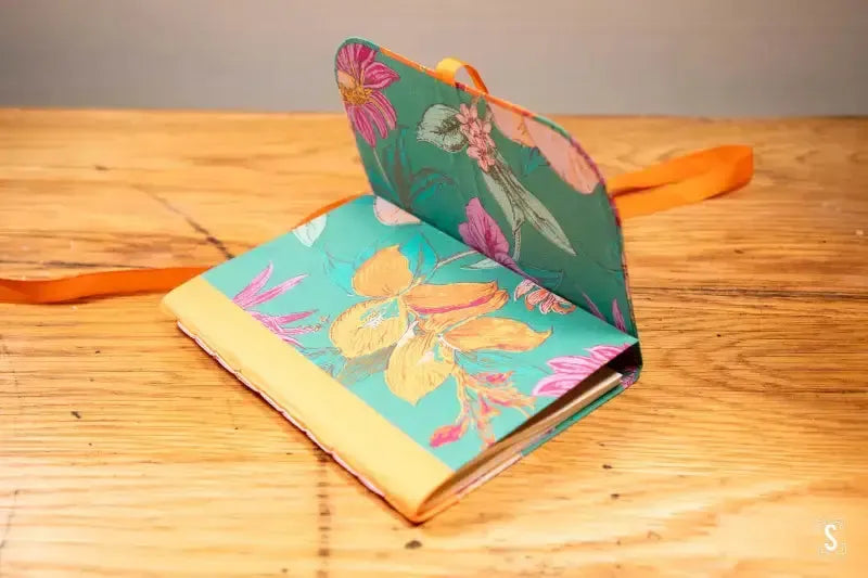 Floral-patterned notebook with turquoise cover showcasing butterfly designs for Chain Stitch Workshop