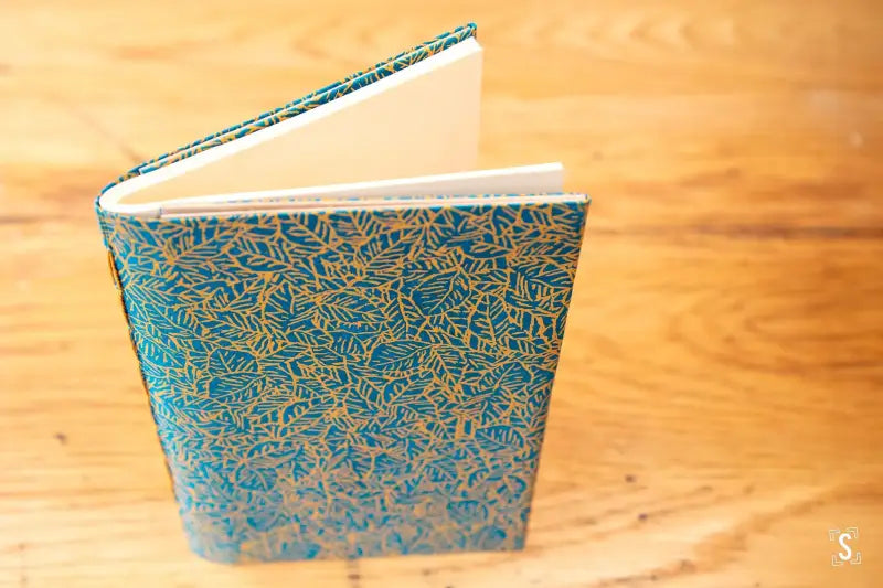 Ornate hardcover book with teal and gold floral design for Bookbinding Workshop Chain Stitch