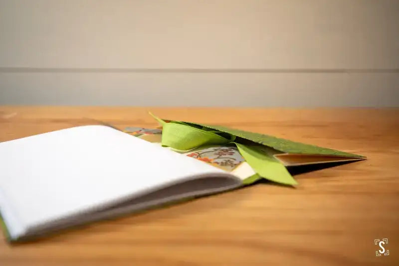 Open notebook with green leaf bookmark for Bookbinding Workshop Chain Stitch