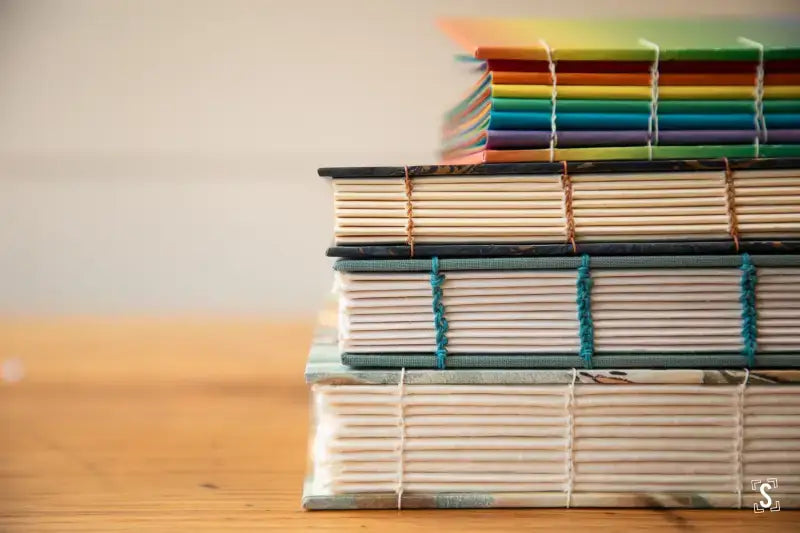 Stack of bound notebooks showcasing the Coptic Stitch in a Bookbinding Workshop