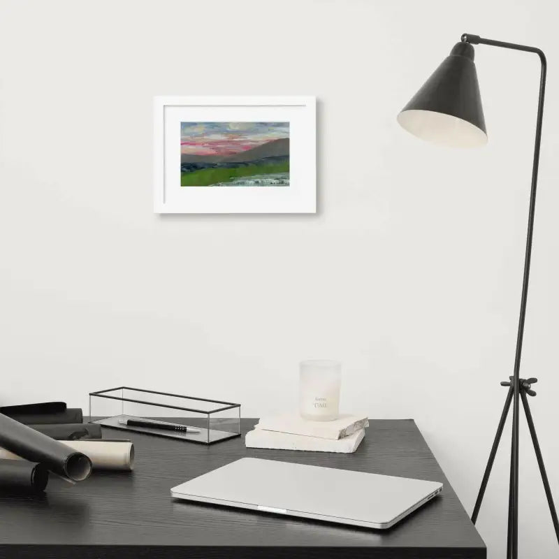 Desk featuring a laptop and lamp beside Framed Poster of Pink Sky Landscape