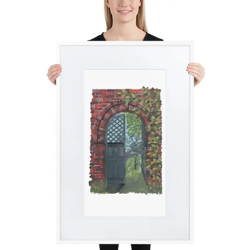 Woman showcasing a framed poster with vibrant colours of a brick wall and door