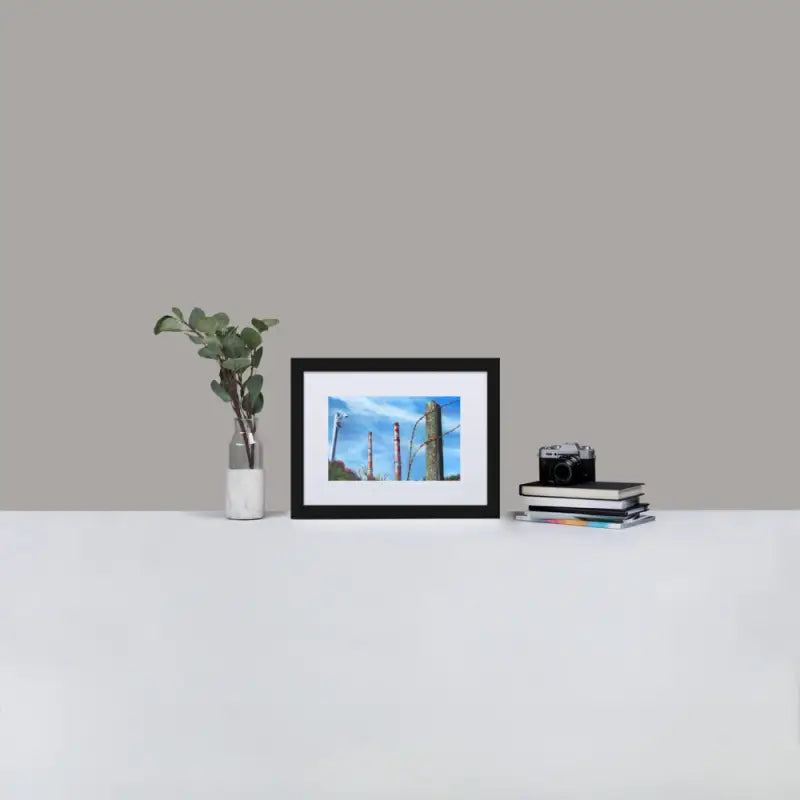 Framed Poster Towers displayed on a white table with a black frame and a plant