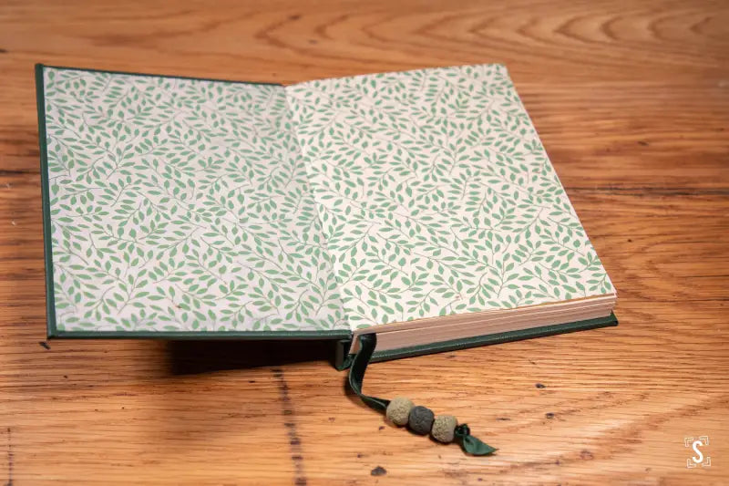 Hand designed book with decorative leaf-patterned cover and beaded bookmark detail