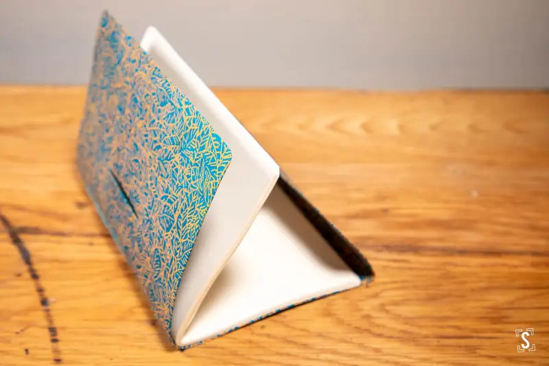 Triangular stand showcasing hand designed blue and green patterned prints for art display