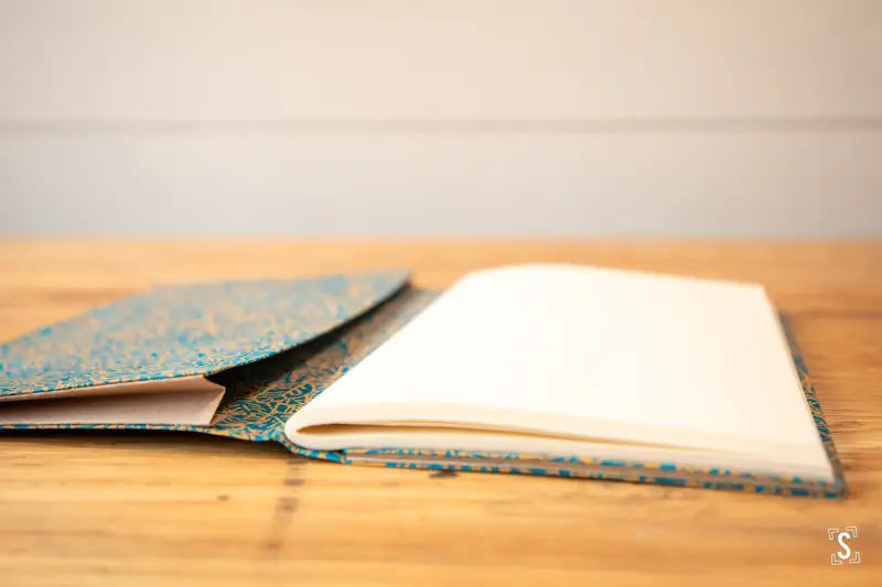 Open Handmade Book featuring a blue and gold patterned cover on rustic wood surface