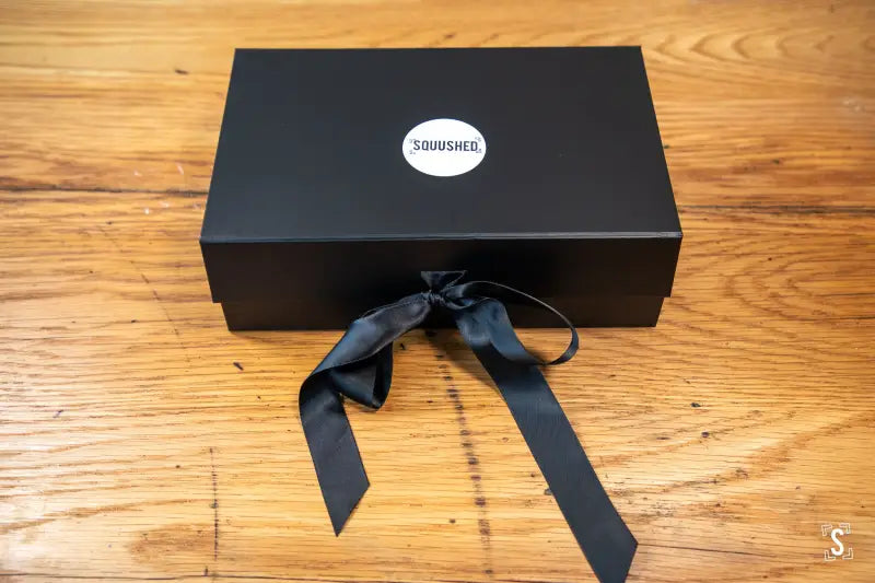 Black gift box featuring Squished logo and ribbon, perfect for hand designed art prints