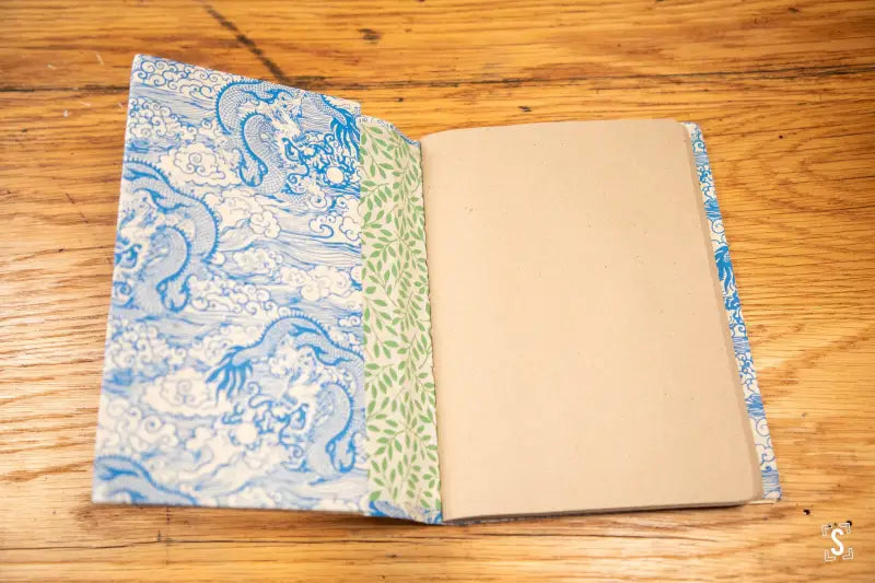 Open book with blue-green patterned cover made of Nepalese Lokta paper on wood