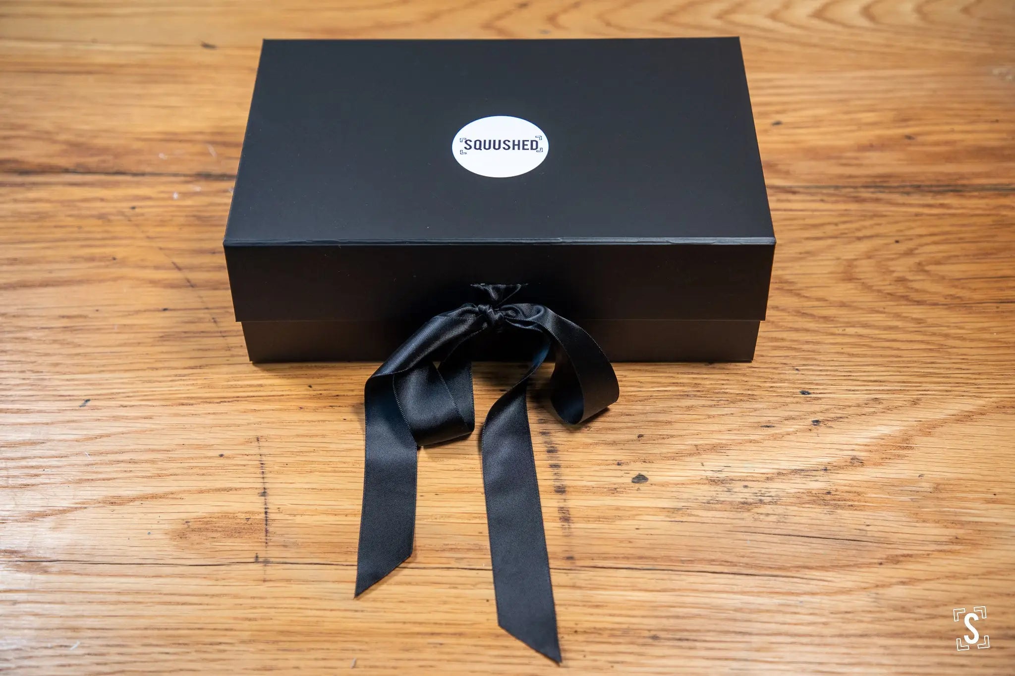 Black gift box with Squushed logo and ribbon, perfect for handmade art prints