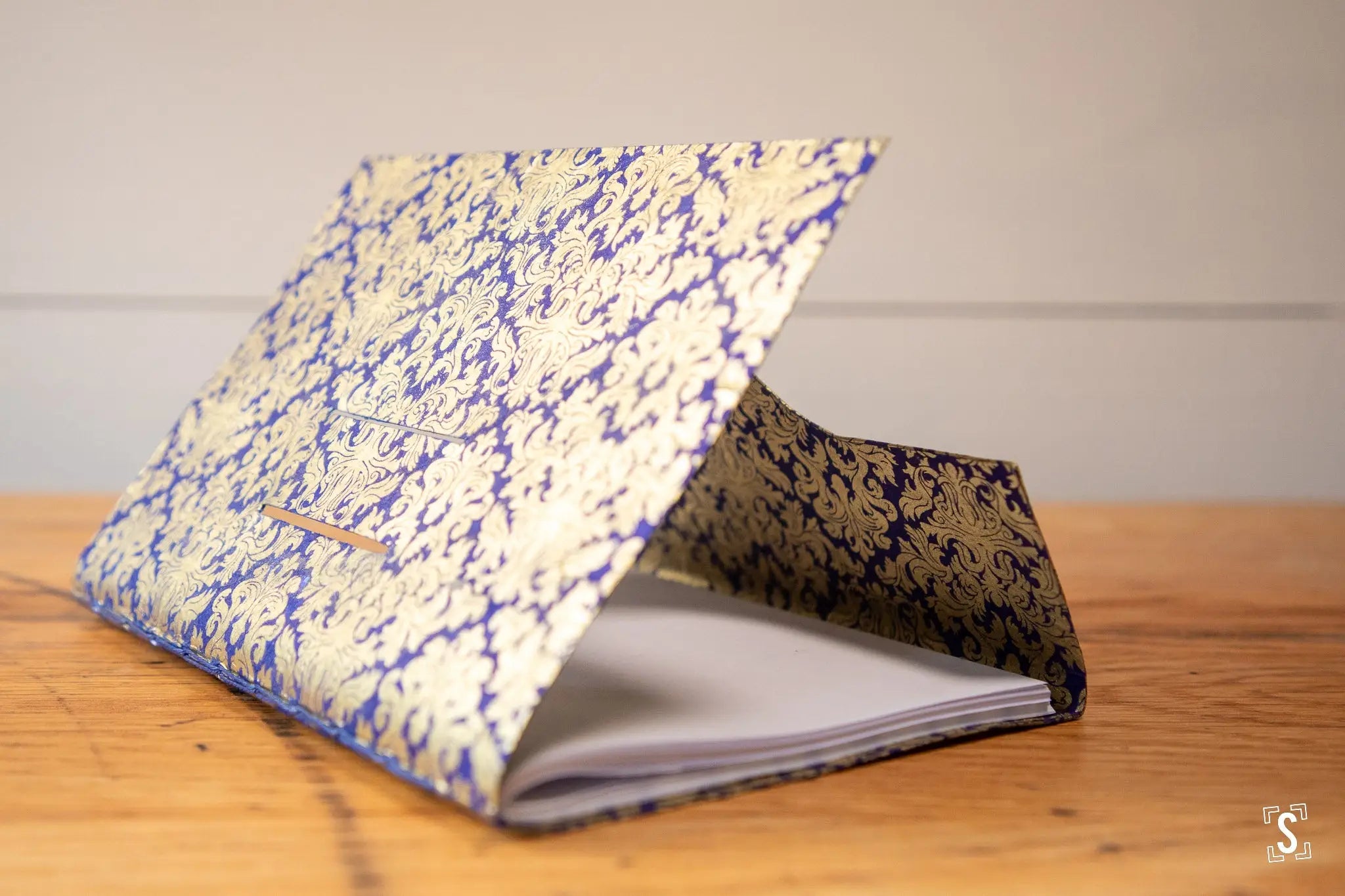 Hand designed Decorative Notebook with blue and gold patterned cover open on a surface