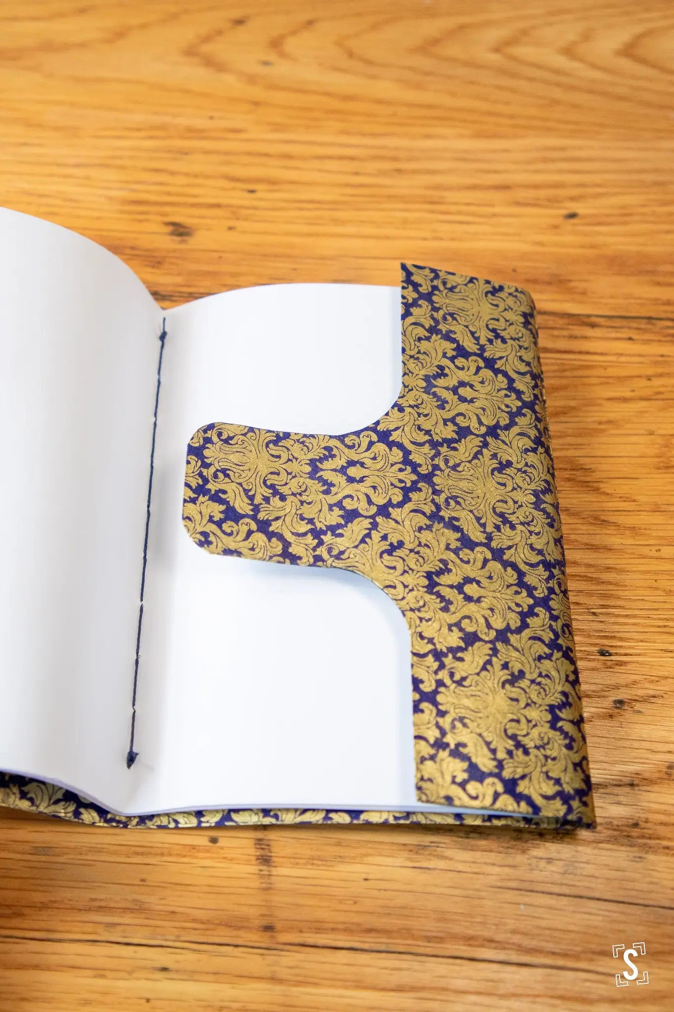 Open notebook featuring ornate gold and purple prints in a handmade design