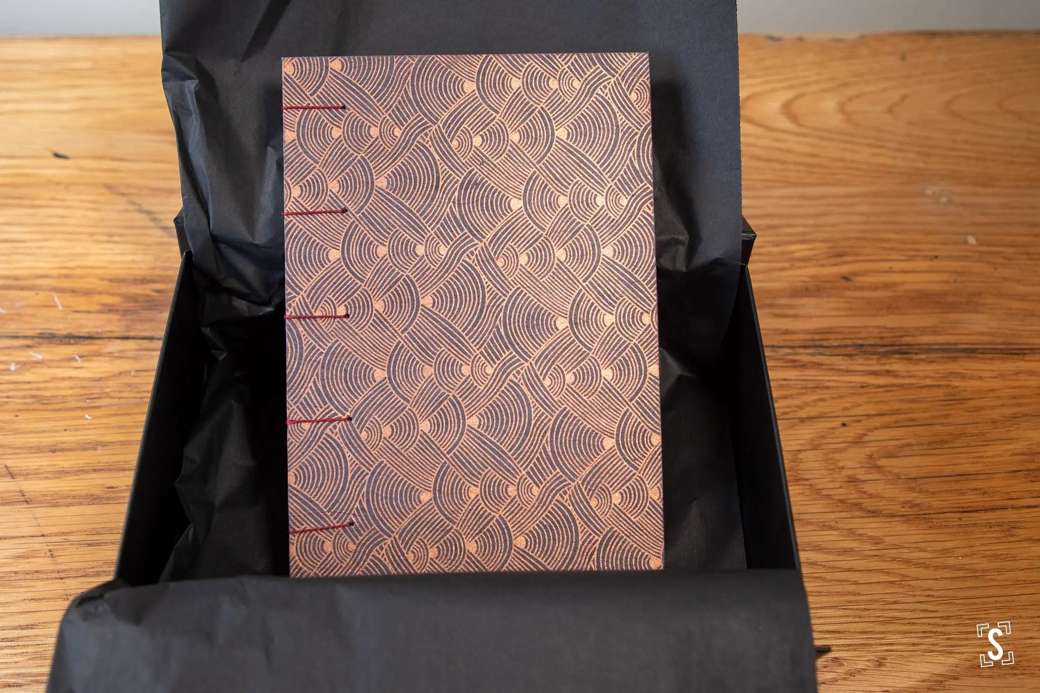 Ornate handmade book with copper cover and intricate art prints, featuring Coptic stitch