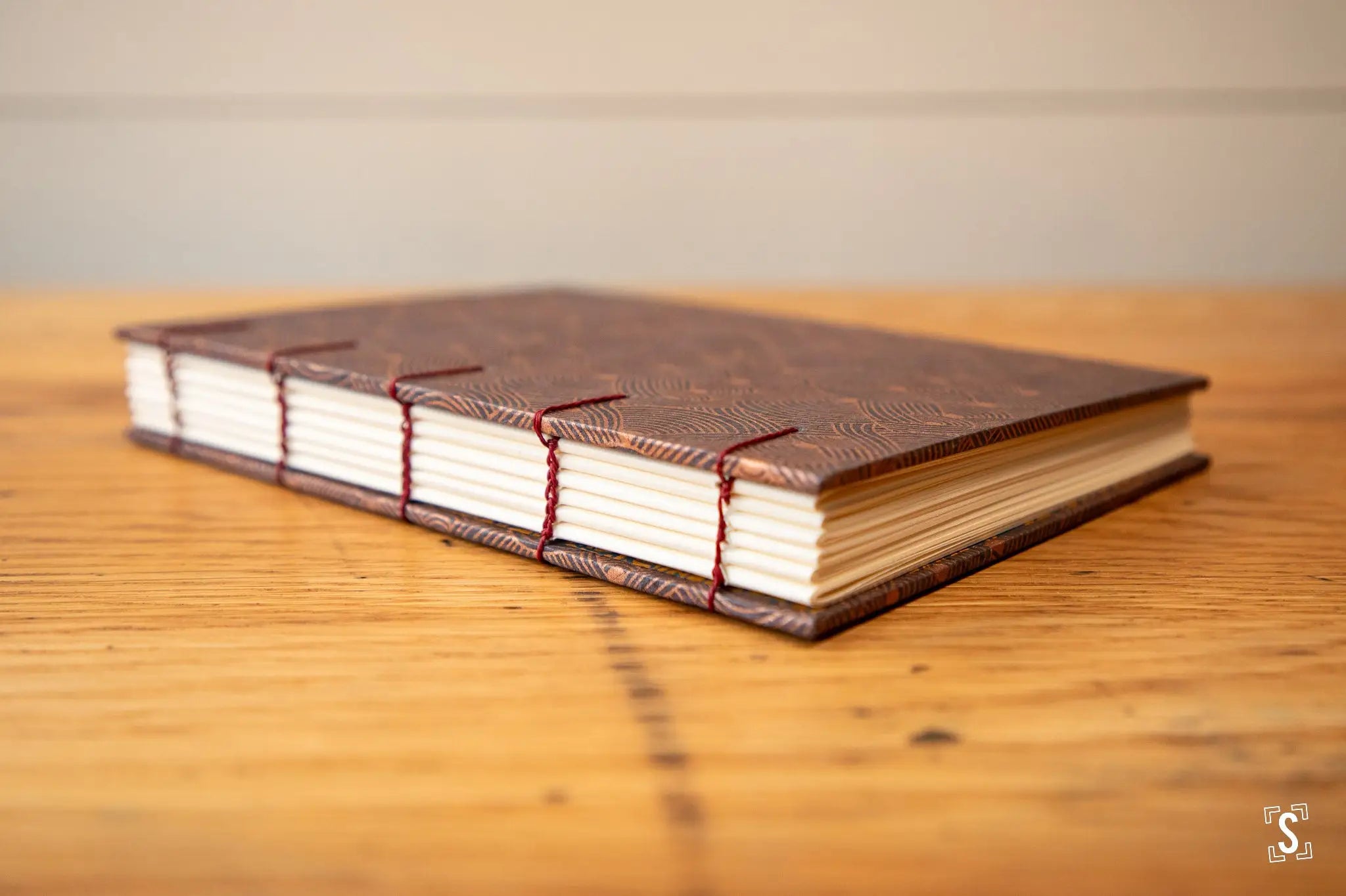 Hand designed handcrafted book with textured brown cover and red stitching, ideal for art prints