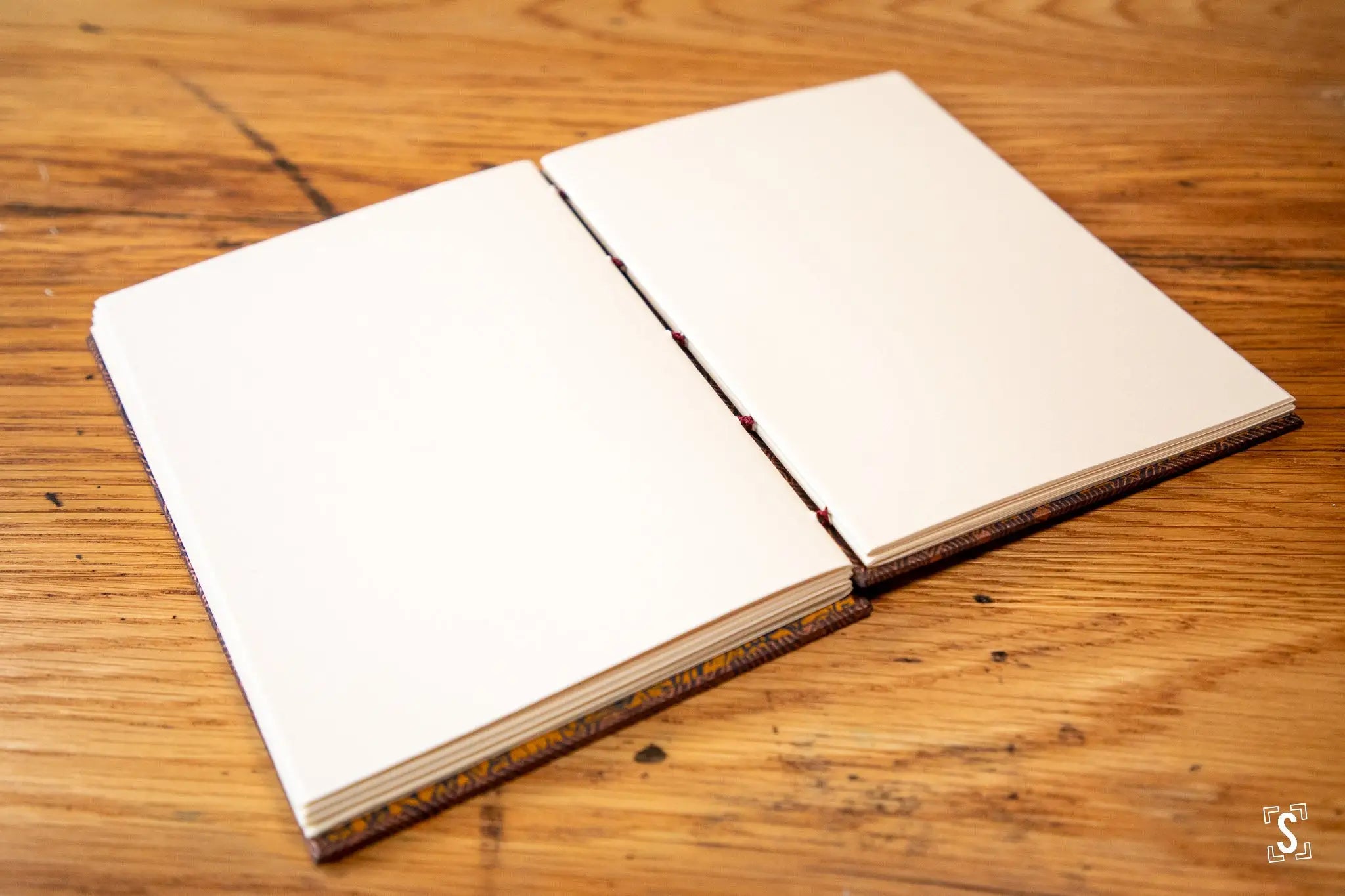 Open blank notebook on wooden surface showcasing handmade design in Nepalese Lokta