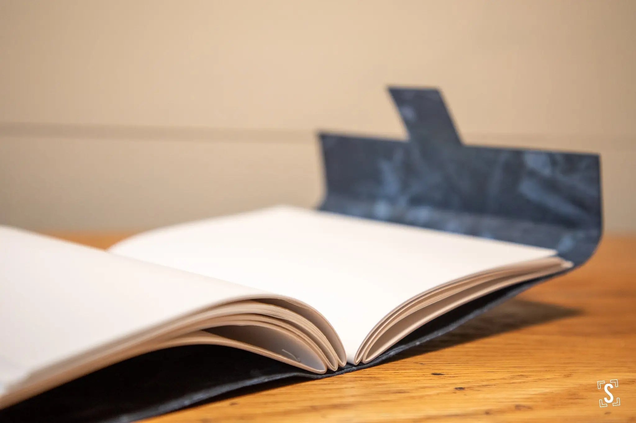 Open book with blank pages on dark cover of Handmade Book featuring artful design