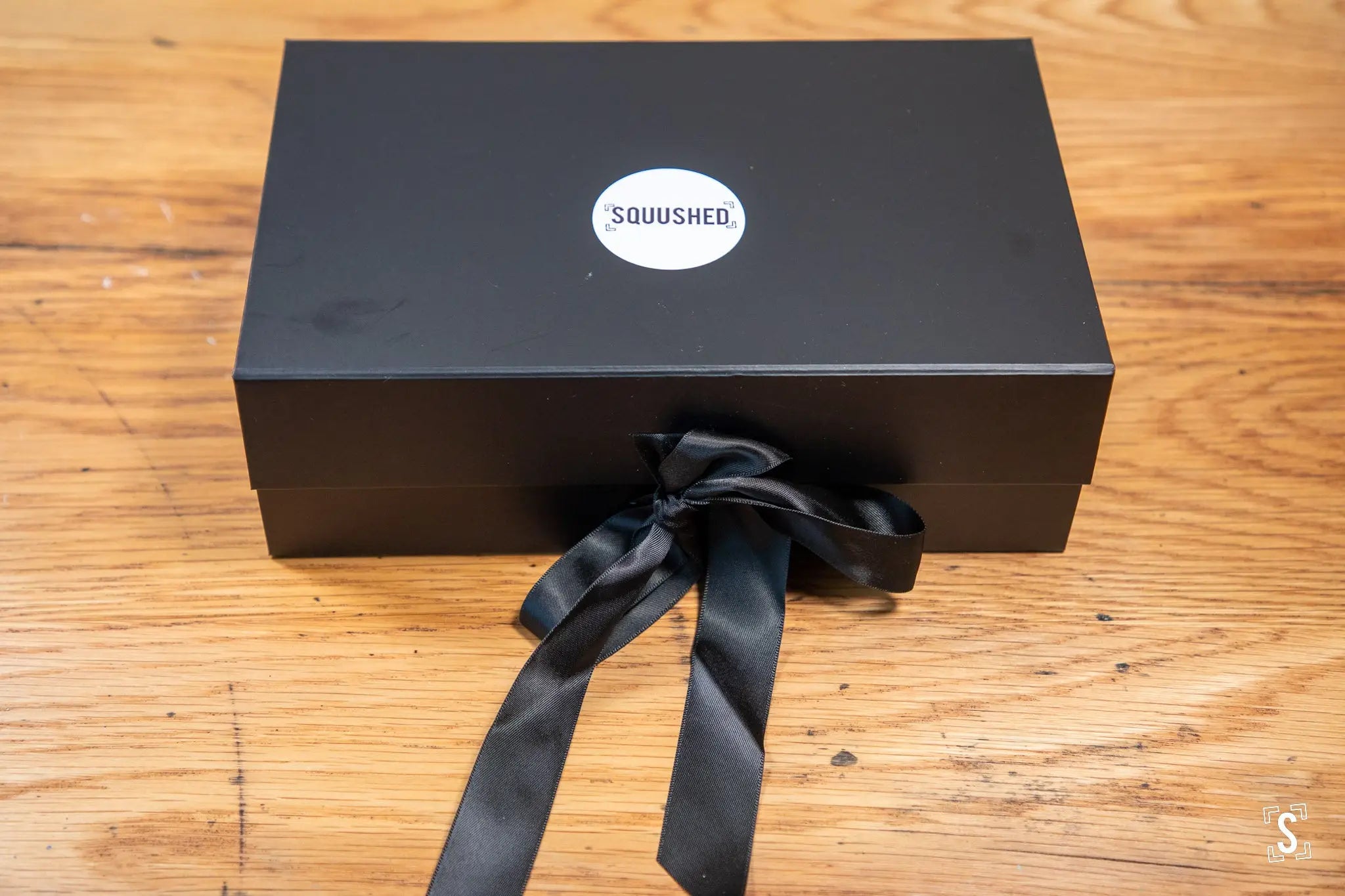 Black gift box featuring SQUUSHED logo and ribbon for Handmade Book art by Nepalese Lokta