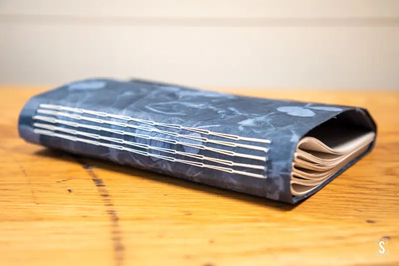 Handmade notebook featuring a dark blue marbled cover and multi-section chain stitch binding