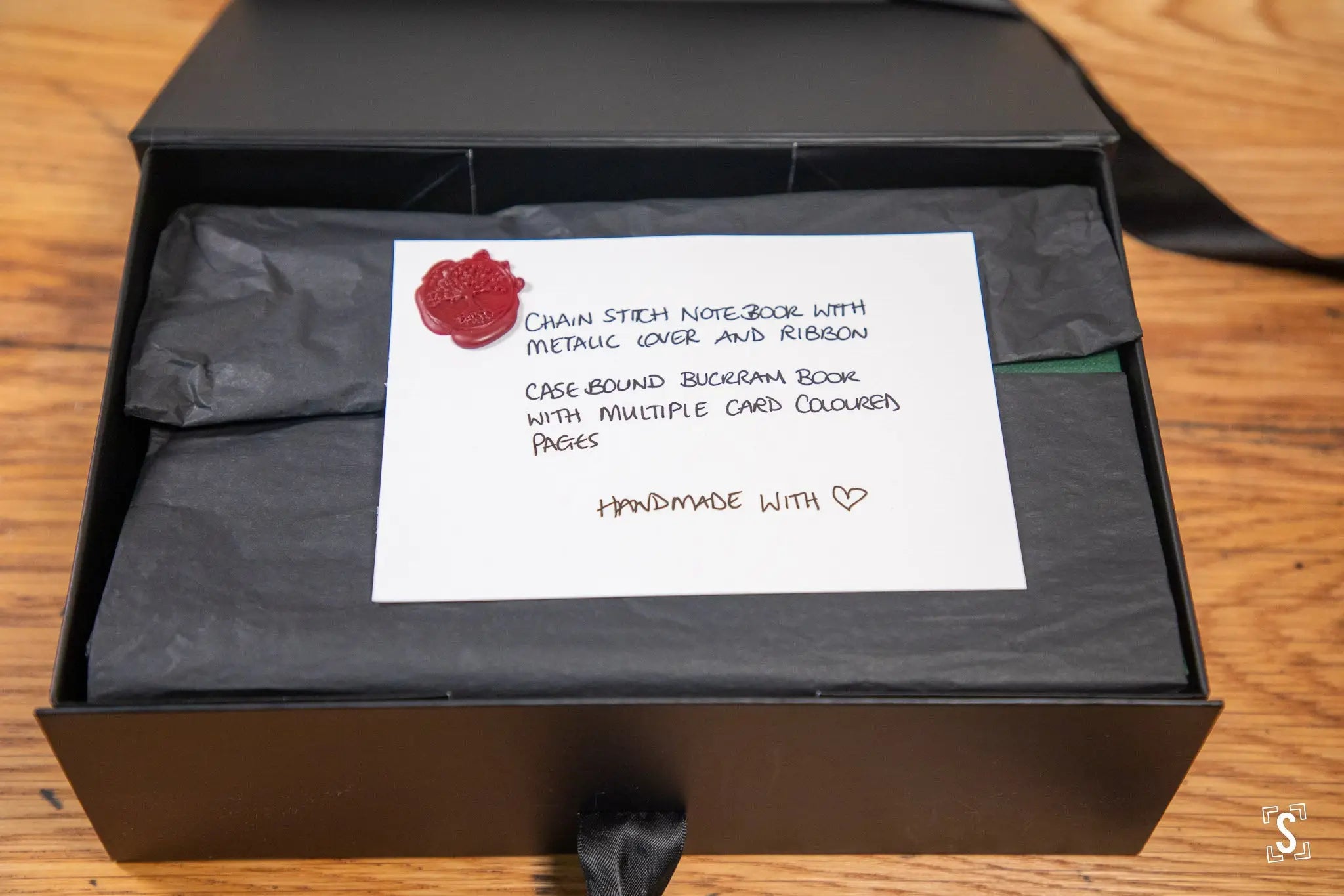 Black gift box with hand designed notebook and note, featuring red wax stamp seal