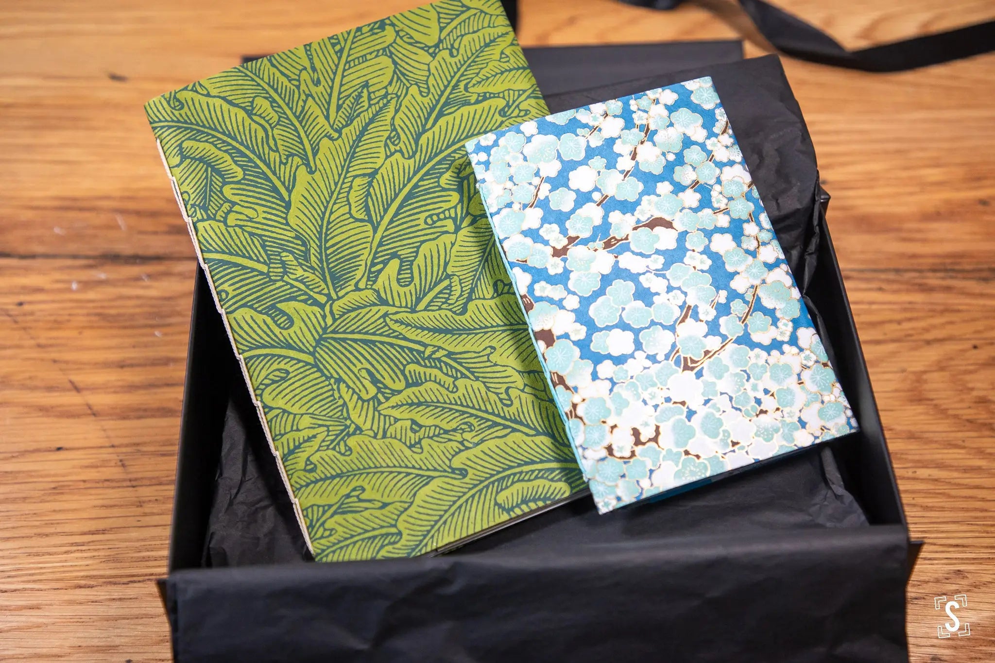 Two hand designed decorative notebooks with patterned covers in a black box