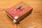 Handmade keepsake box with pink and gold pattern and metallic handle for storage