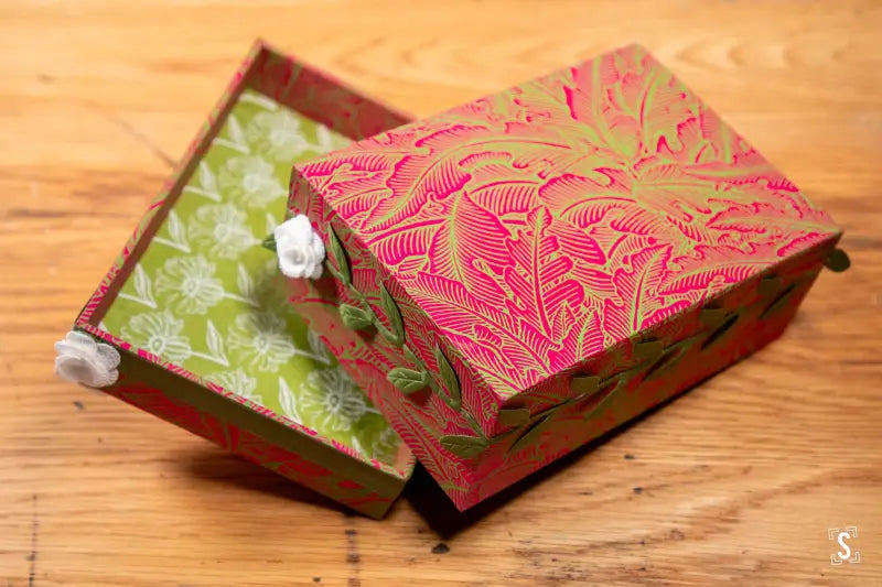 Two decorative handmade keepsake boxes featuring intricate floral patterns in pink and green