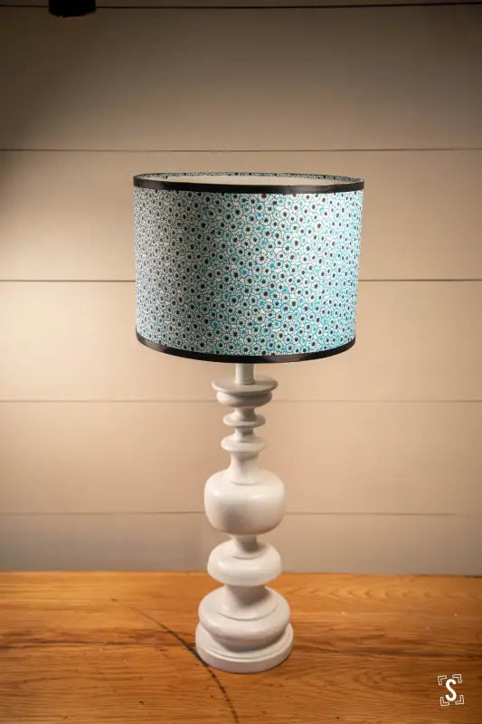 Table lamp featuring a white turned base and light blue polka-dotted lampshade