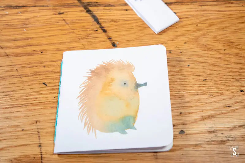 Watercolor painting of a cute hedgehog on a handmade notebook with chain stitch binding