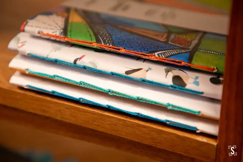 Stack of colorful handmade notebooks showcasing chain stitch binding and unique designs