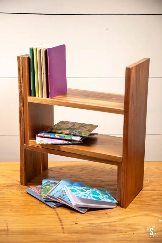 Wooden bookshelf with books showcasing the Handmade Pocket Notebook on display