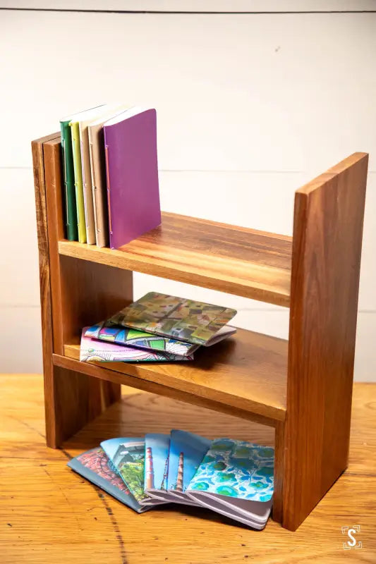 Wooden bookshelf with books and notebooks, featuring a Handmade Pocket Notebook