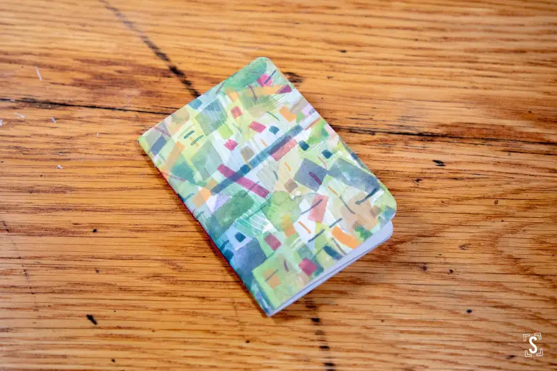 Colorful patterned handmade pocket notebook displayed on a wooden surface