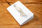 White notepad with bird illustration on a Handmade Pocket Notebook cover