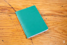 Teal-colored Handmade Pocket Notebook on a wooden surface showcasing its unique design