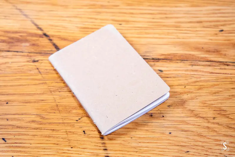 White handmade pocket notebook on a rustic wooden surface, perfect for notes and sketches