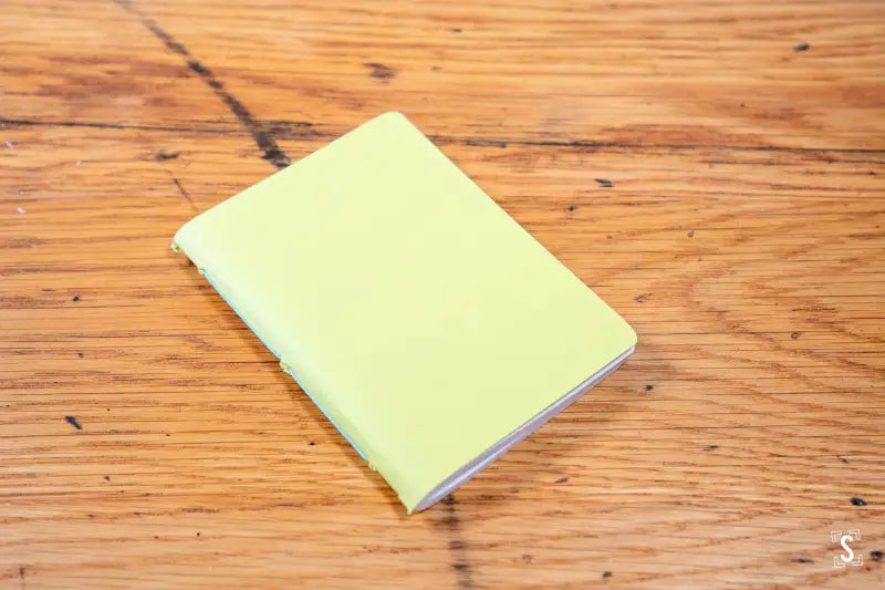 Pale yellow handmade pocket notebook on a wooden surface for stylish note-taking