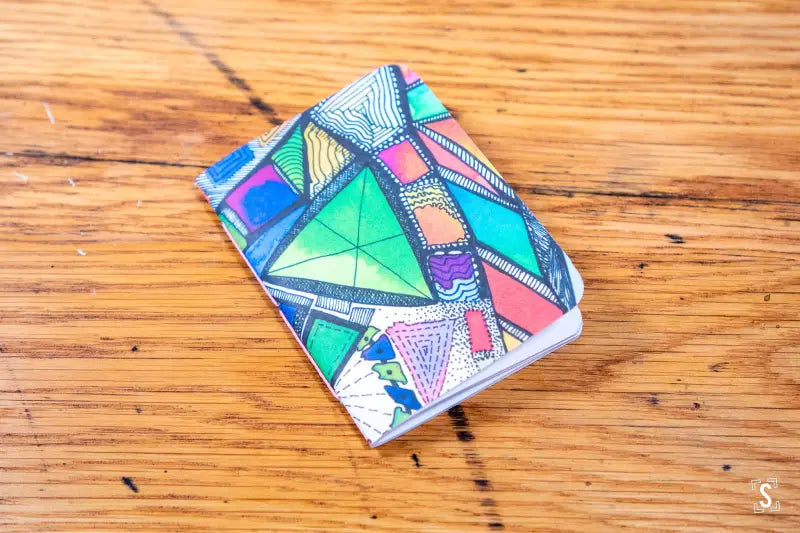 Colorful geometric patterned Handmade Pocket Notebook on a wooden surface