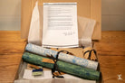 Document atop rolled parchment paper and scrolls in a box of Coptic Stitch bookbinding materials