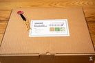 Cardboard box with shipping label and wax seal for Coptic Stitch bookbinding materials