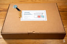 Cardboard shipping box with delivery label and blue key for Coptic Stitch bookbinding materials