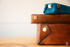 Stack of leather cases with metallic snap closures from Leathercraft Workshop products