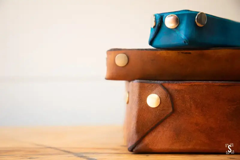 Stack of leather cases with metallic snap closures for the No-Sew Leather Box