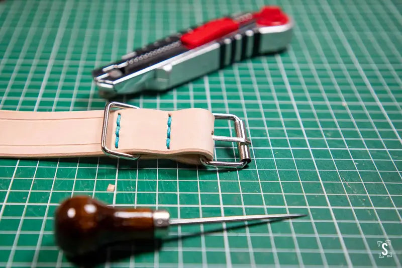 Leather watch strap and tools on cutting mat at Leathercraft Workshop for pet collar